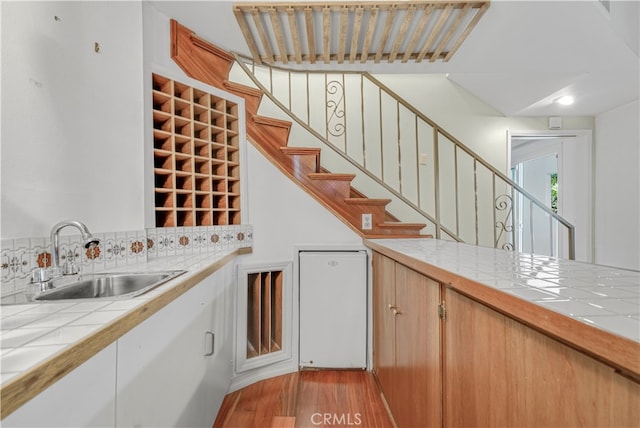 interior space featuring backsplash, sink, light wood-type flooring, and tile counters