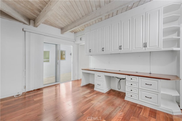 unfurnished office featuring built in desk, beam ceiling, light wood-type flooring, and wooden ceiling