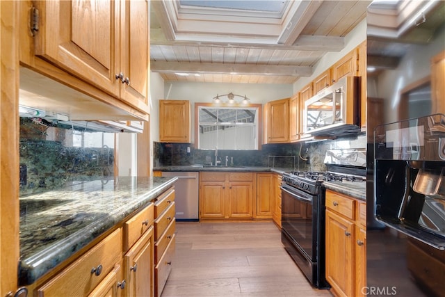 kitchen featuring a wealth of natural light, beam ceiling, appliances with stainless steel finishes, and light hardwood / wood-style flooring