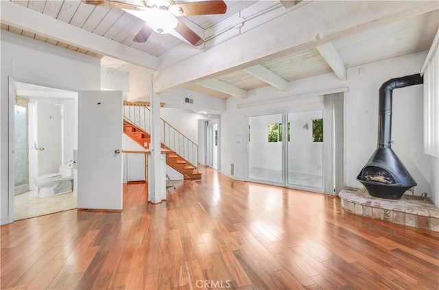 interior space featuring a wood stove, beamed ceiling, wood-type flooring, and wood ceiling