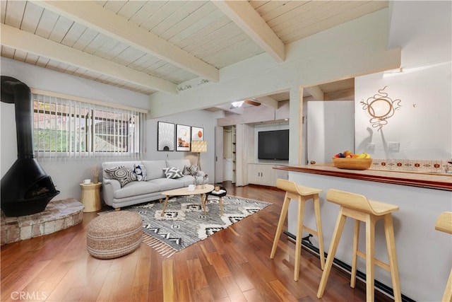 living room featuring a wood stove, beamed ceiling, and wood-type flooring