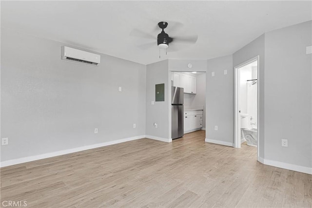 unfurnished living room with electric panel, ceiling fan, a wall mounted air conditioner, and light wood-type flooring