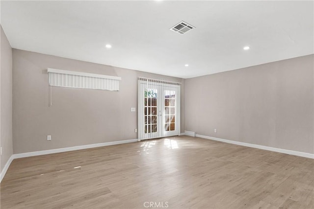 spare room featuring french doors and light hardwood / wood-style flooring