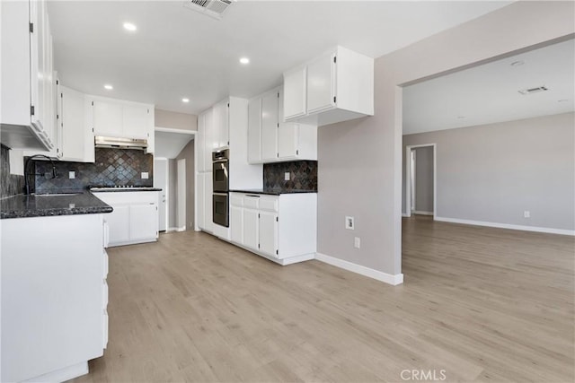 kitchen with backsplash, sink, stainless steel double oven, light wood-type flooring, and white cabinetry