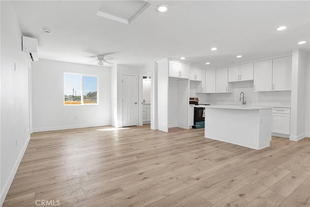 kitchen featuring a center island with sink, stainless steel electric range, light hardwood / wood-style floors, and white cabinetry