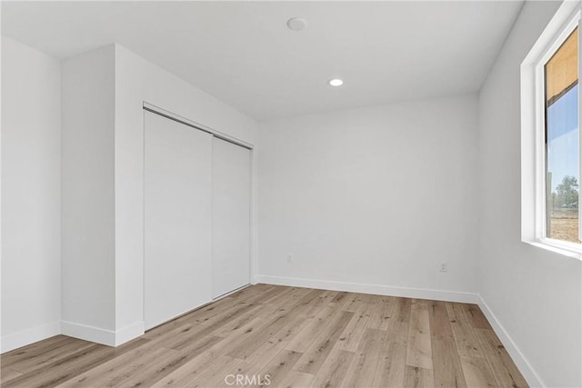 unfurnished bedroom with a closet and light hardwood / wood-style flooring