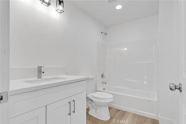 full bathroom with shower / tub combination, vanity, wood-type flooring, and toilet