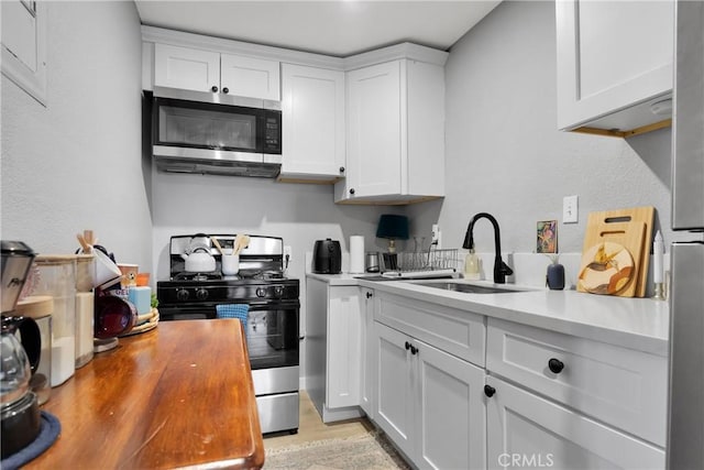 kitchen featuring sink, white cabinets, light hardwood / wood-style flooring, and appliances with stainless steel finishes