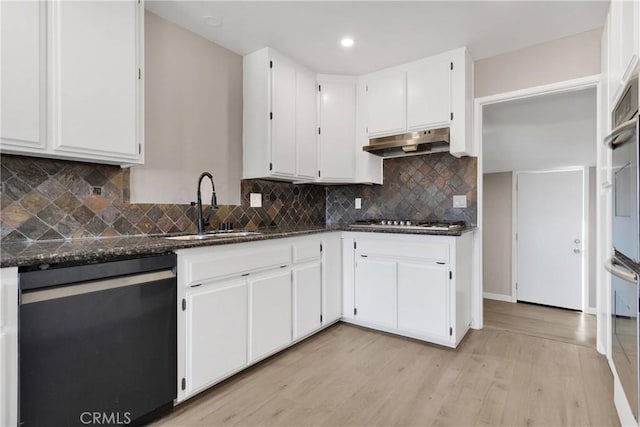 kitchen featuring appliances with stainless steel finishes, sink, light hardwood / wood-style flooring, dark stone countertops, and white cabinetry