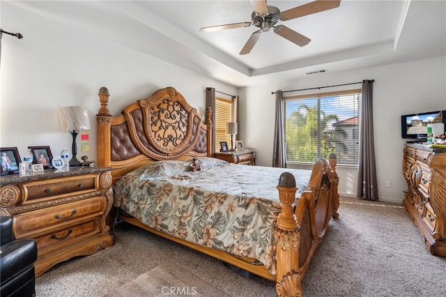 carpeted bedroom featuring a tray ceiling and ceiling fan