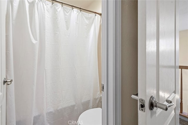 bathroom featuring a shower with curtain and toilet