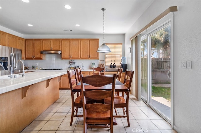 kitchen with stainless steel fridge, tile counters, pendant lighting, and plenty of natural light