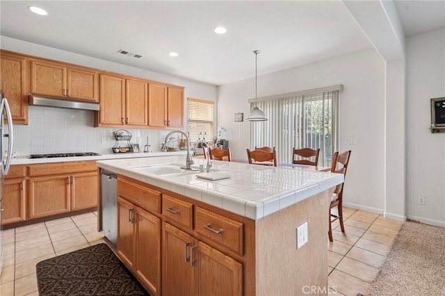 kitchen featuring gas stovetop, a kitchen island with sink, sink, pendant lighting, and dishwasher