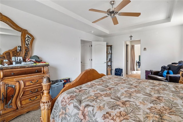 bedroom featuring a raised ceiling, ceiling fan, and light colored carpet