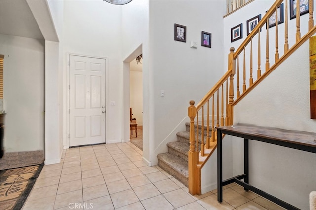 foyer entrance featuring a towering ceiling and light tile patterned flooring