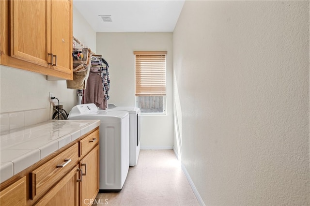 laundry room featuring cabinets and washing machine and dryer