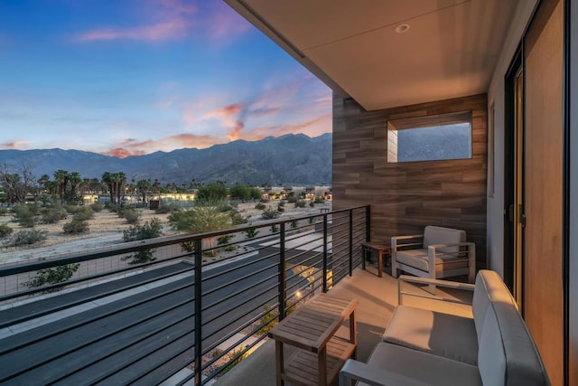 balcony at dusk featuring a mountain view and an outdoor living space