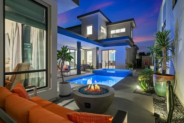 exterior space featuring a swimming pool with hot tub, a patio area, and an outdoor living space with a fire pit