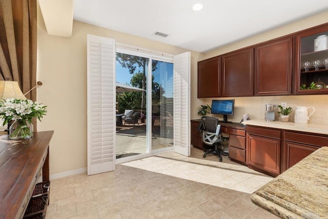 home office featuring built in study area, visible vents, and baseboards