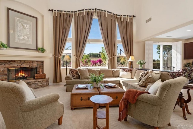 sitting room with visible vents, a stone fireplace, and a towering ceiling