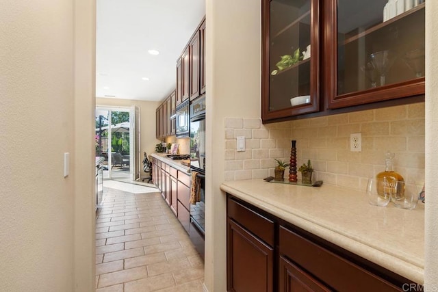 kitchen with light countertops, gas cooktop, glass insert cabinets, and decorative backsplash