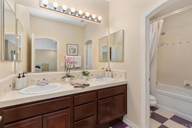 bathroom with toilet, double vanity, a sink, and shower / tub combo with curtain