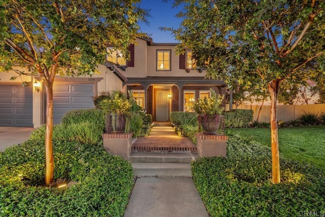 view of front of home with a garage, concrete driveway, fence, and stucco siding