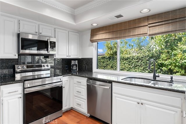 kitchen with white cabinets, sink, stainless steel appliances, and dark stone counters