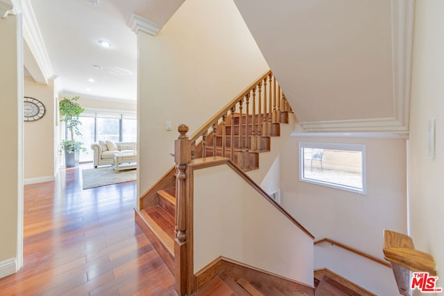 stairway with ornate columns, ornamental molding, and wood-type flooring