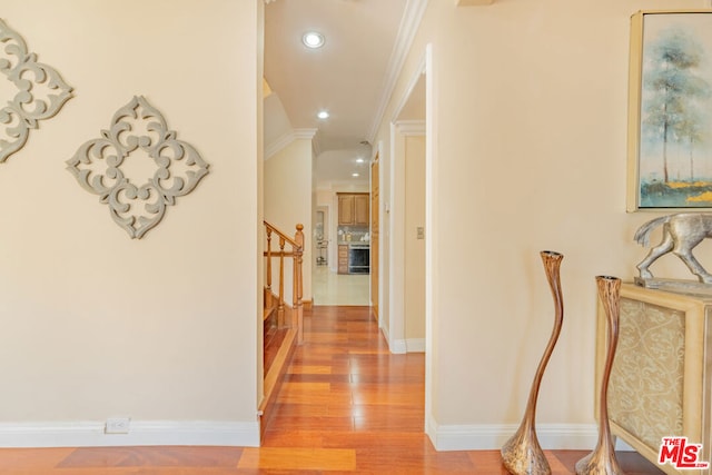 hallway with crown molding and light wood-type flooring