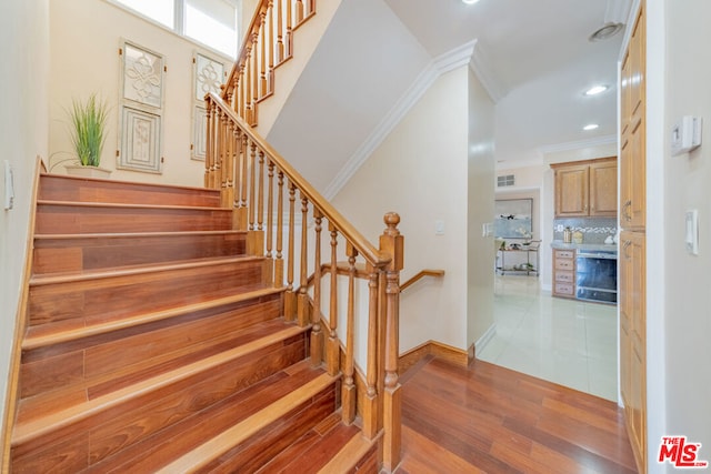 stairway featuring hardwood / wood-style floors and ornamental molding