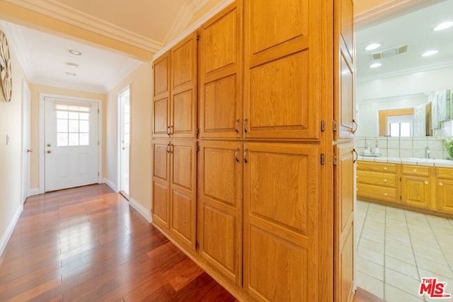 hall with light wood-type flooring and ornamental molding