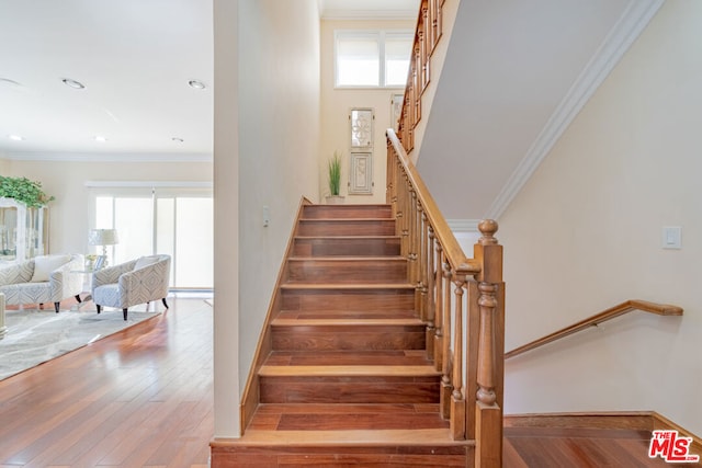 stairway featuring wood-type flooring and ornamental molding