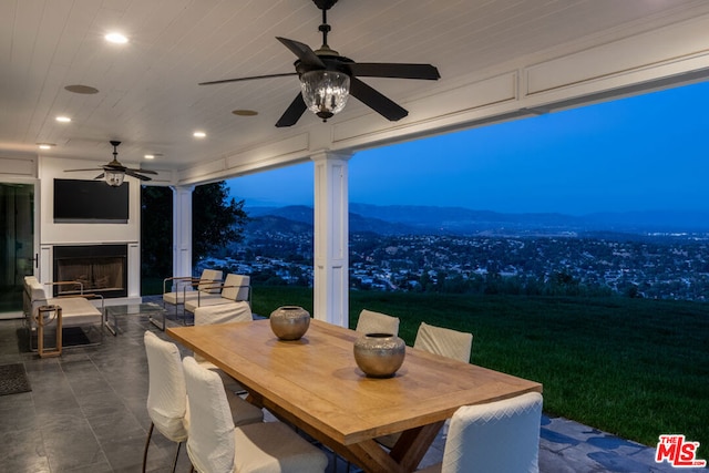 view of patio / terrace featuring an outdoor fireplace, ceiling fan, and a mountain view