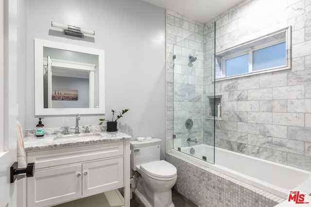 full bathroom featuring shower / bath combination with glass door, vanity, and toilet