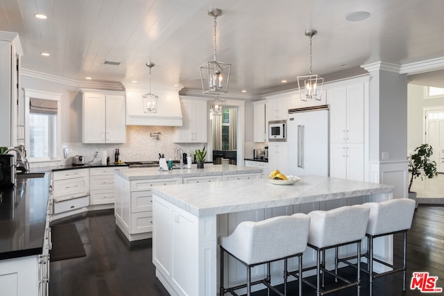 kitchen with white cabinetry, dark wood-type flooring, built in appliances, pendant lighting, and a center island