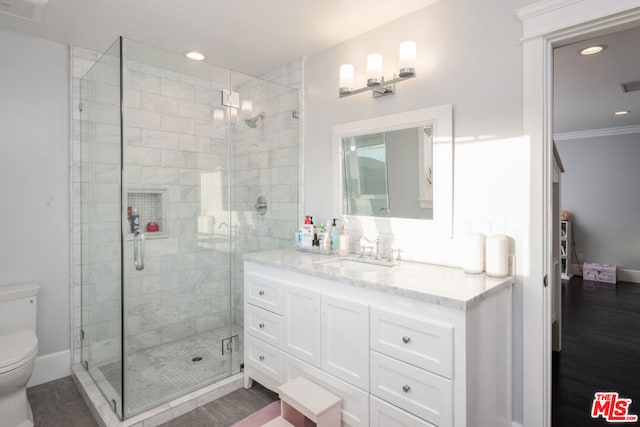 bathroom featuring hardwood / wood-style flooring, walk in shower, crown molding, vanity, and toilet