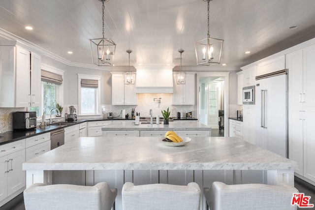 kitchen featuring white cabinetry, a spacious island, a kitchen bar, and decorative light fixtures