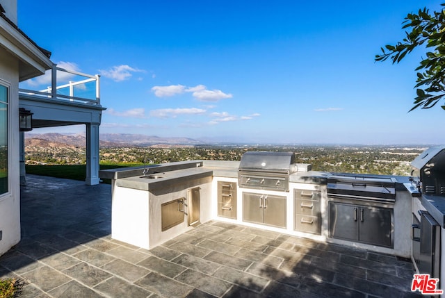 view of patio with area for grilling, an outdoor kitchen, and a mountain view