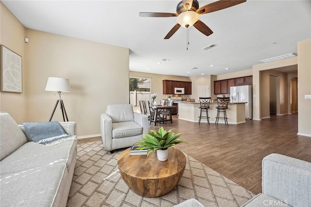 living room with ceiling fan and dark hardwood / wood-style flooring