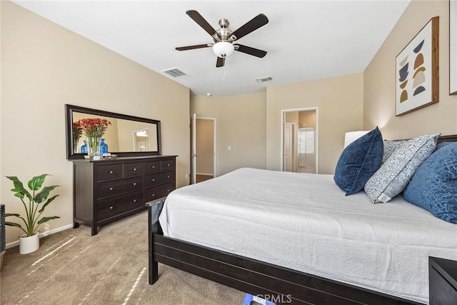 bedroom with ceiling fan, light colored carpet, and ensuite bathroom