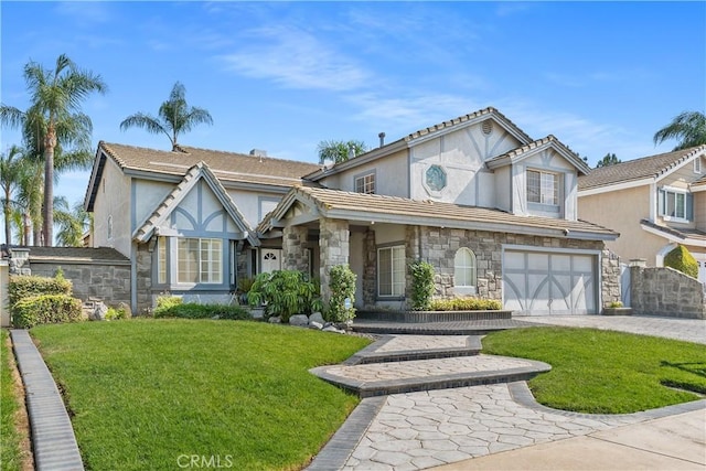 tudor-style house featuring a front yard and a garage