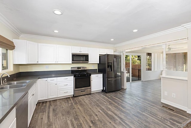 kitchen with appliances with stainless steel finishes, dark hardwood / wood-style flooring, ornamental molding, sink, and white cabinetry