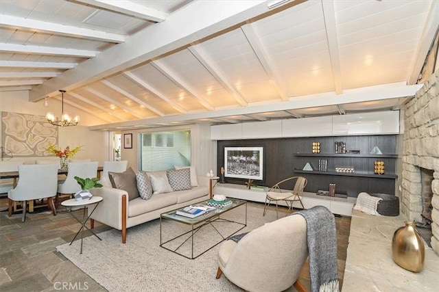 living room with a notable chandelier, lofted ceiling with beams, and a fireplace