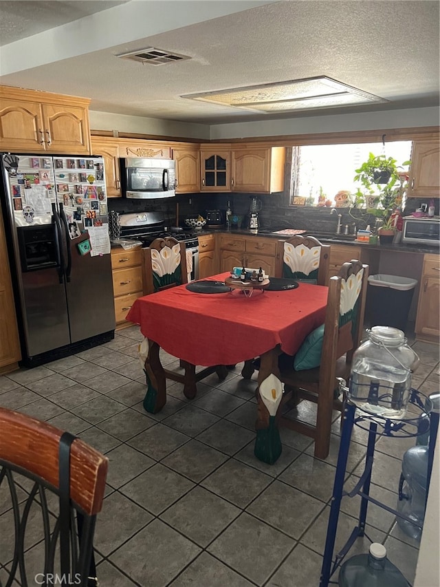 kitchen with decorative backsplash, appliances with stainless steel finishes, and tile patterned floors