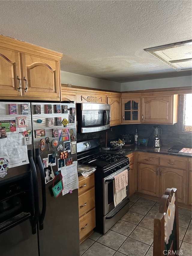 kitchen with stainless steel appliances, light tile patterned floors, and a textured ceiling