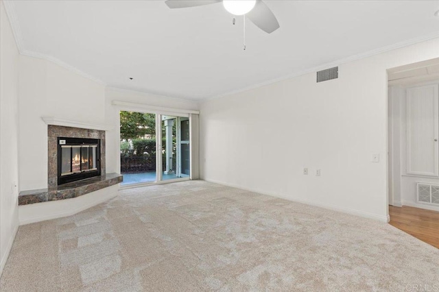 unfurnished living room featuring light carpet, ceiling fan, a premium fireplace, and ornamental molding