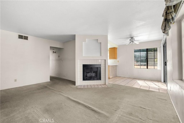 unfurnished living room featuring ceiling fan, light colored carpet, and a fireplace