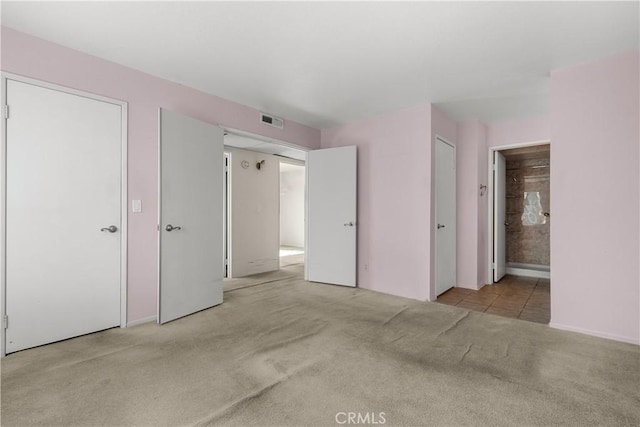 unfurnished bedroom with connected bathroom and light colored carpet