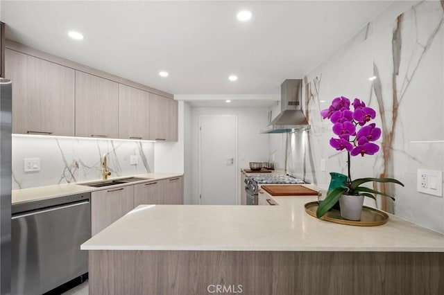 kitchen with dishwasher, sink, light brown cabinets, wall chimney exhaust hood, and range